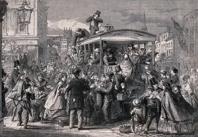 Many people are riding on and crowding around a large horse-drawn carriage