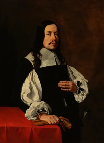Portrait of a man standing by a table draped with a red cloth, holding his gloves