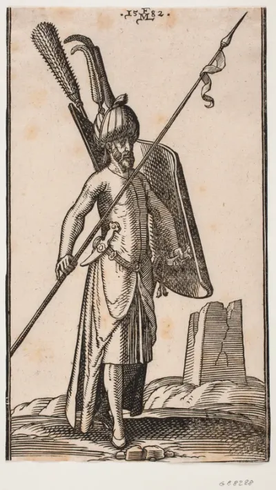 Stående soldat med krumt skjold i v. hånd og i h. hånd et spyd, der holdes skråt; sværd ved hans v. side, en dolk stukket i bæltet ved hans v. side; i baggrunden t.h. ruinen af en obelisk eller et tårn med kvadratisk grundplan