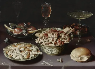 Still life of porcelain vessels containing sweets, pewter plates bearing sweets and chestnuts, three pieces of glassware and a bread roll on a table draped with a mauve cloth