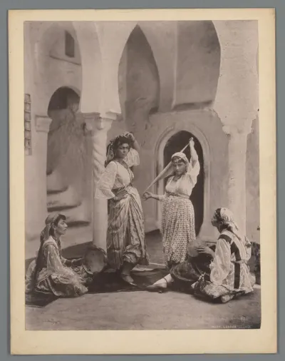 Twee danseressen en twee vrouwen met tamboerijn op een binnenplaats, vermoedelijk te Algiers, Algerije