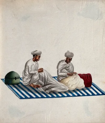 Two men sitting on a carpet, engaged in needle work