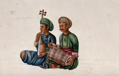 Two musicians playing a dholak (percussion instrument) and a tanpura (stringed instrument)