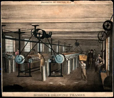 Women are working at large cotton machines, a child is carrying a basket on his head, and other people are sitting on benches at the side of the room