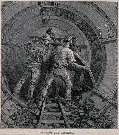 Workmen fitting metal casings to form an underground tunnel